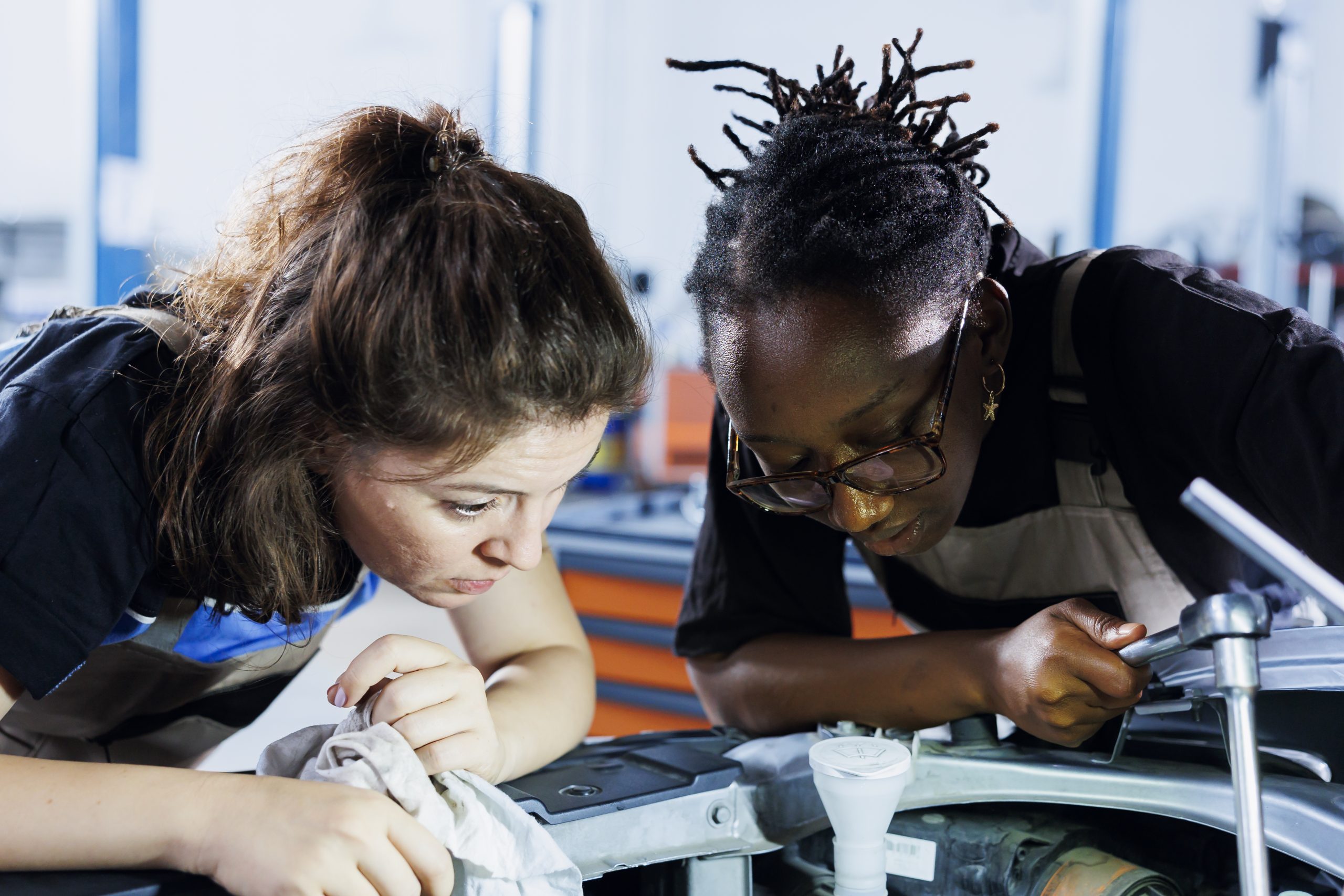 women in repair shop fixing vehicle